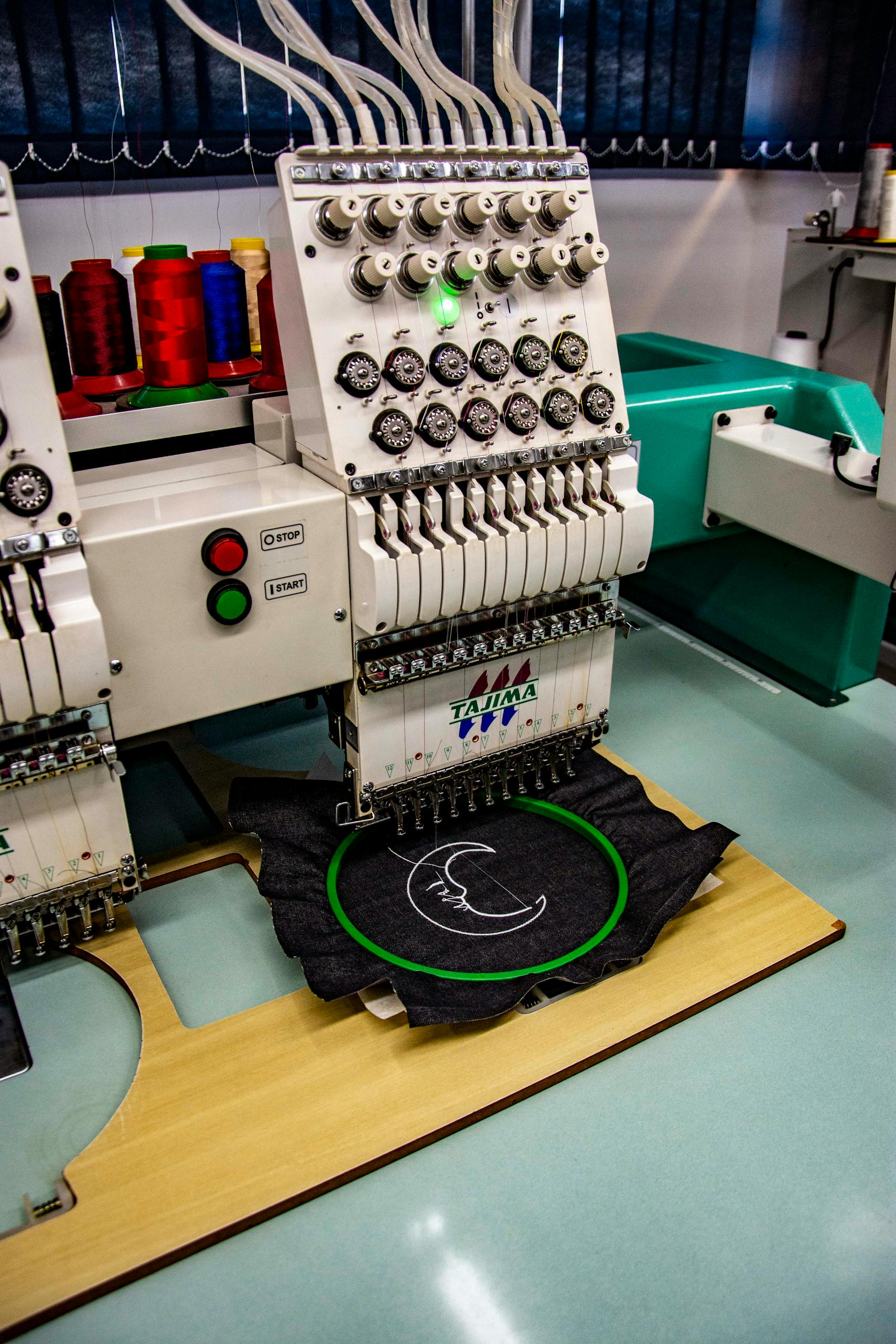 High-quality embroidery machine stitching fabric in an industrial setting in Apucarana, Brazil.